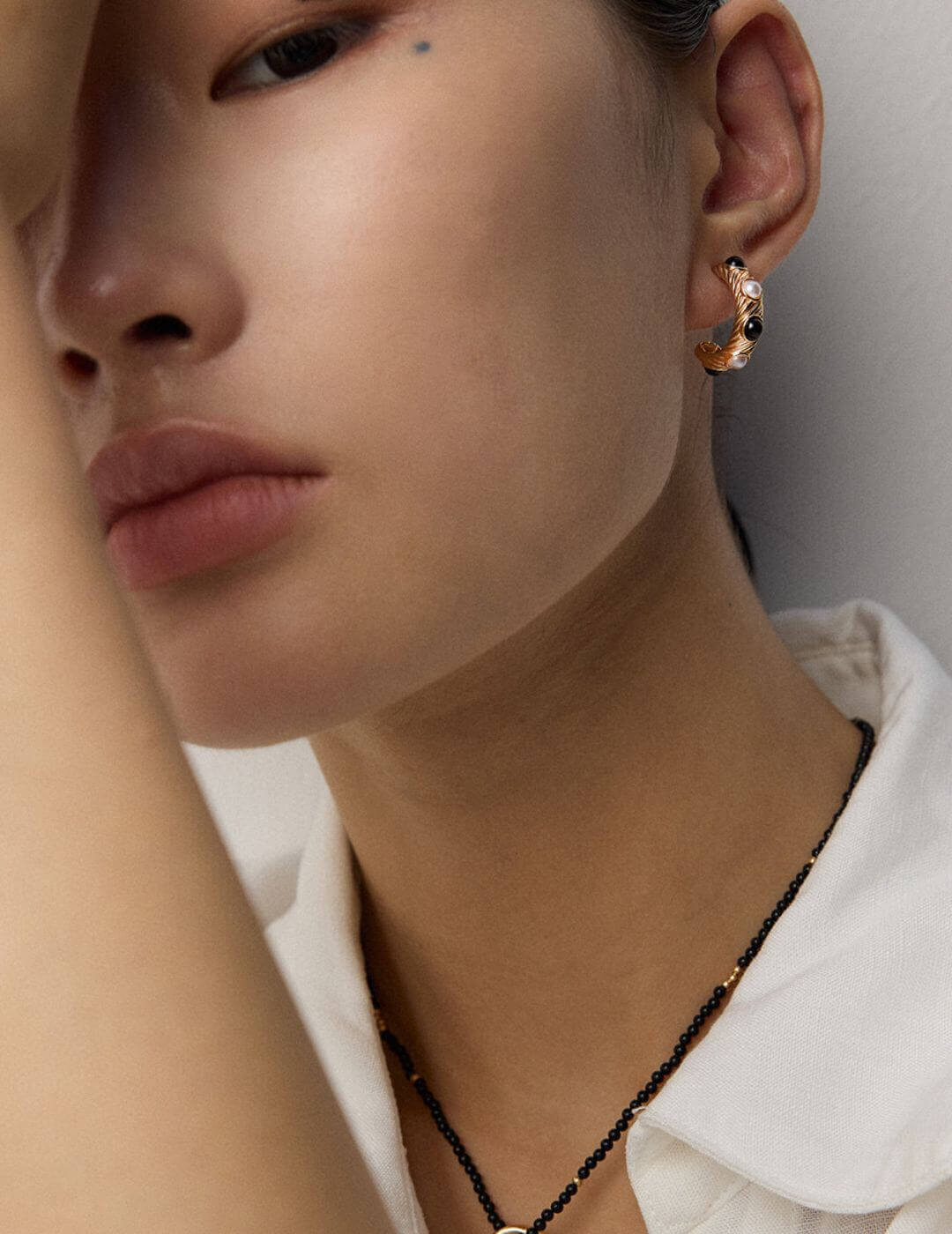 Side view of white gold pearl and onyx stud earrings on model, highlighting fresh vitality.