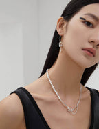 Front view of the artistic asymmetric earrings, highlighting the balance between the 'withered vine' and 'new nest' pearl.