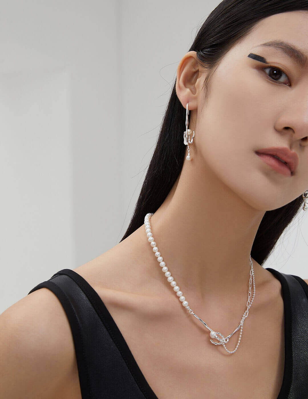 Front view of the artistic asymmetric earrings, highlighting the balance between the 'withered vine' and 'new nest' pearl.