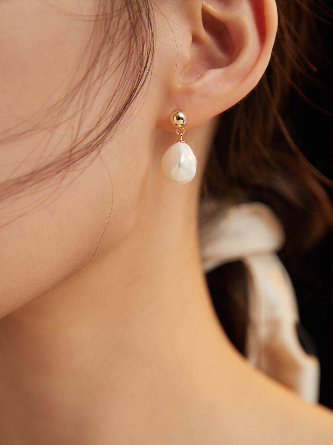 A woman elegantly wearing the vintage baroque natural pearl and sterling silver earrings, showing how they frame the face.