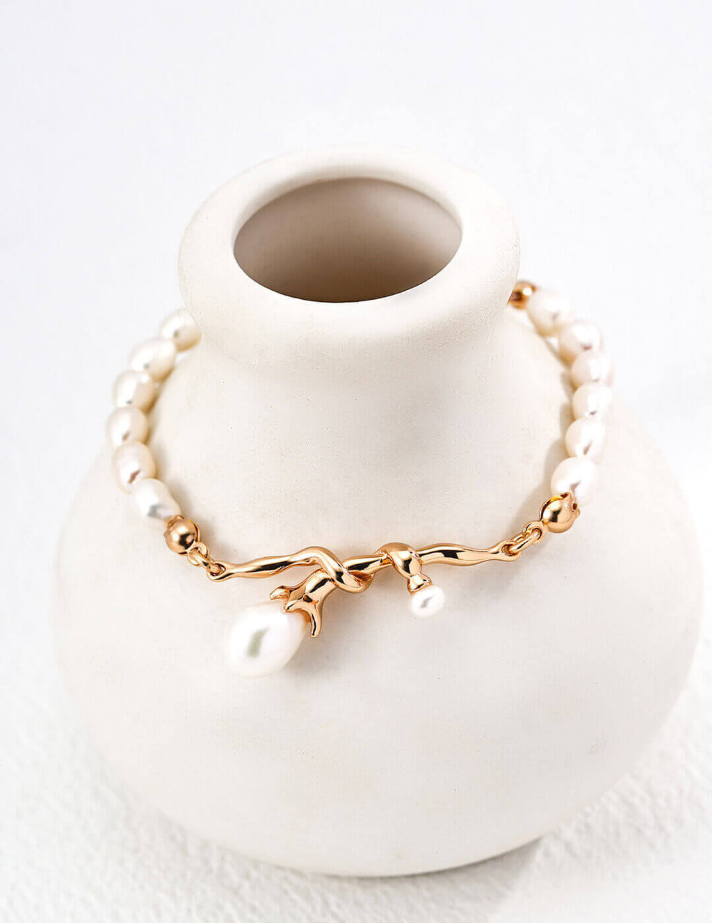 Gold bracelet with pearls on a white vase