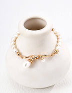 Gold bracelet with pearls on a white vase