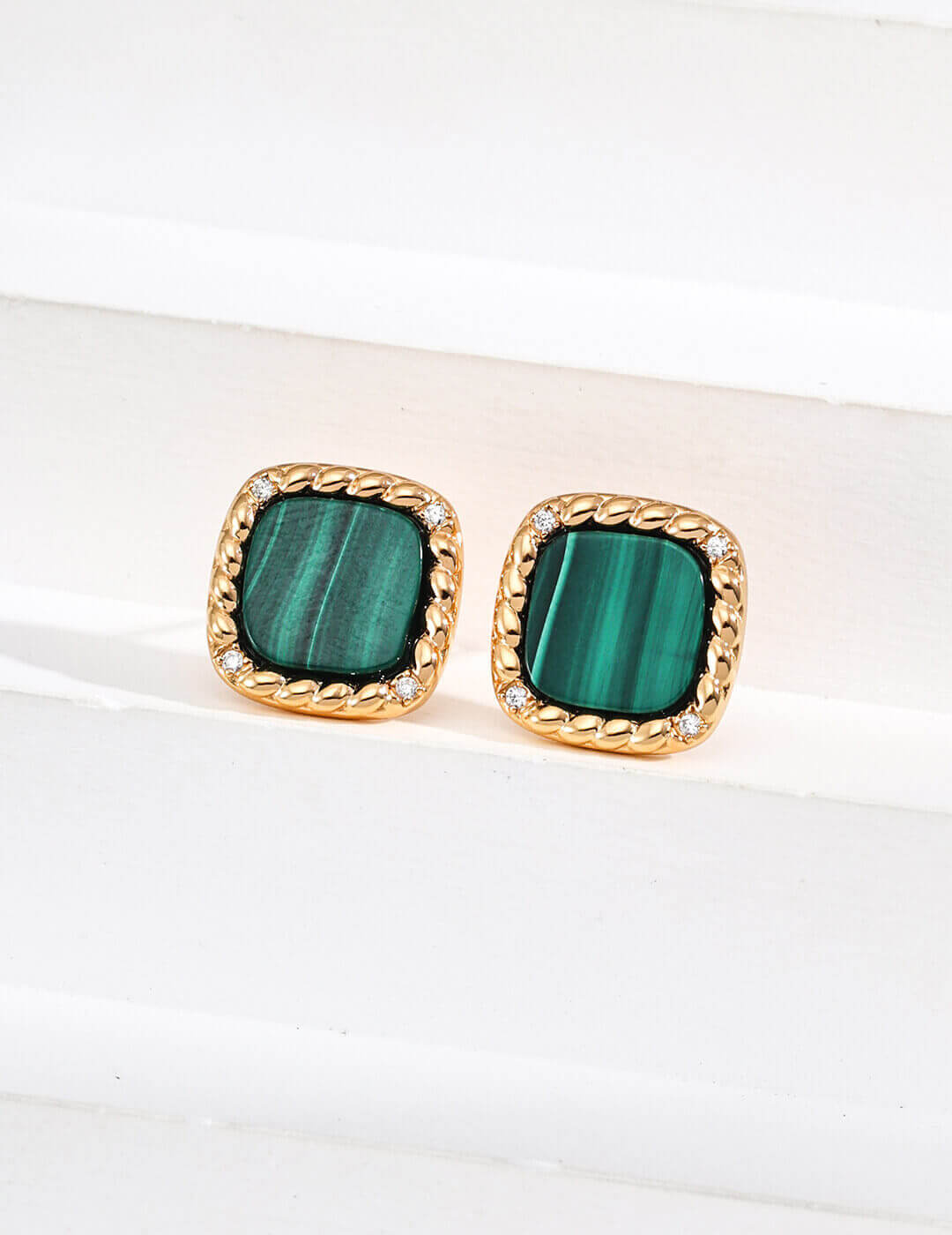 Pair of green square earrings with gold accents on a white surface