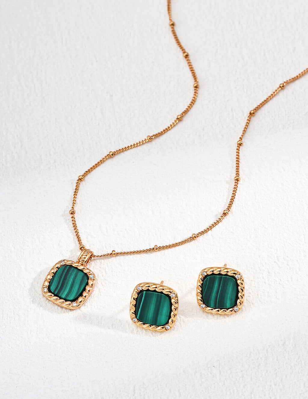 Jewelry set with green stones and gold accents on a white background